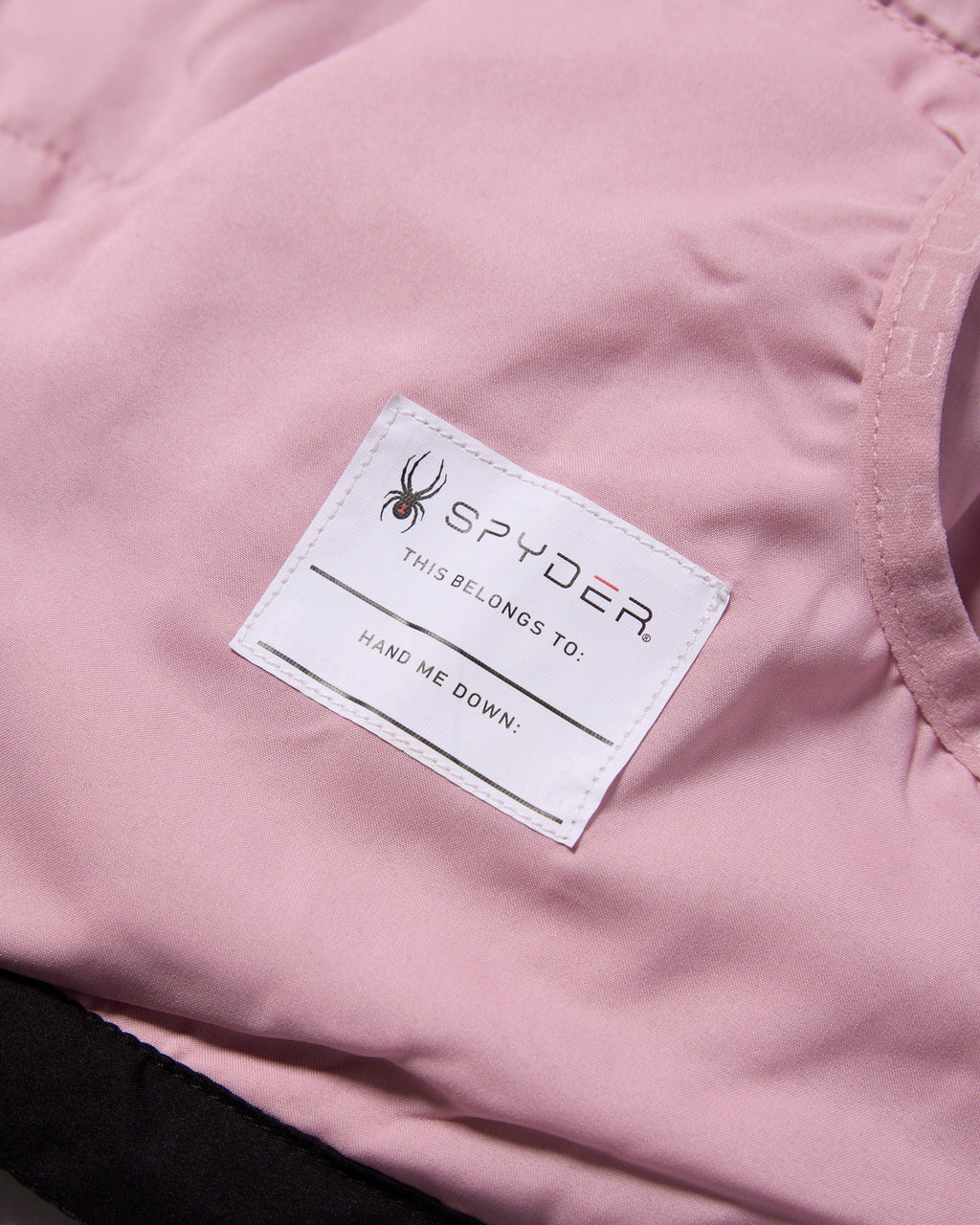 Close-up of a pink jacket with a Spyder label on a matching pink background