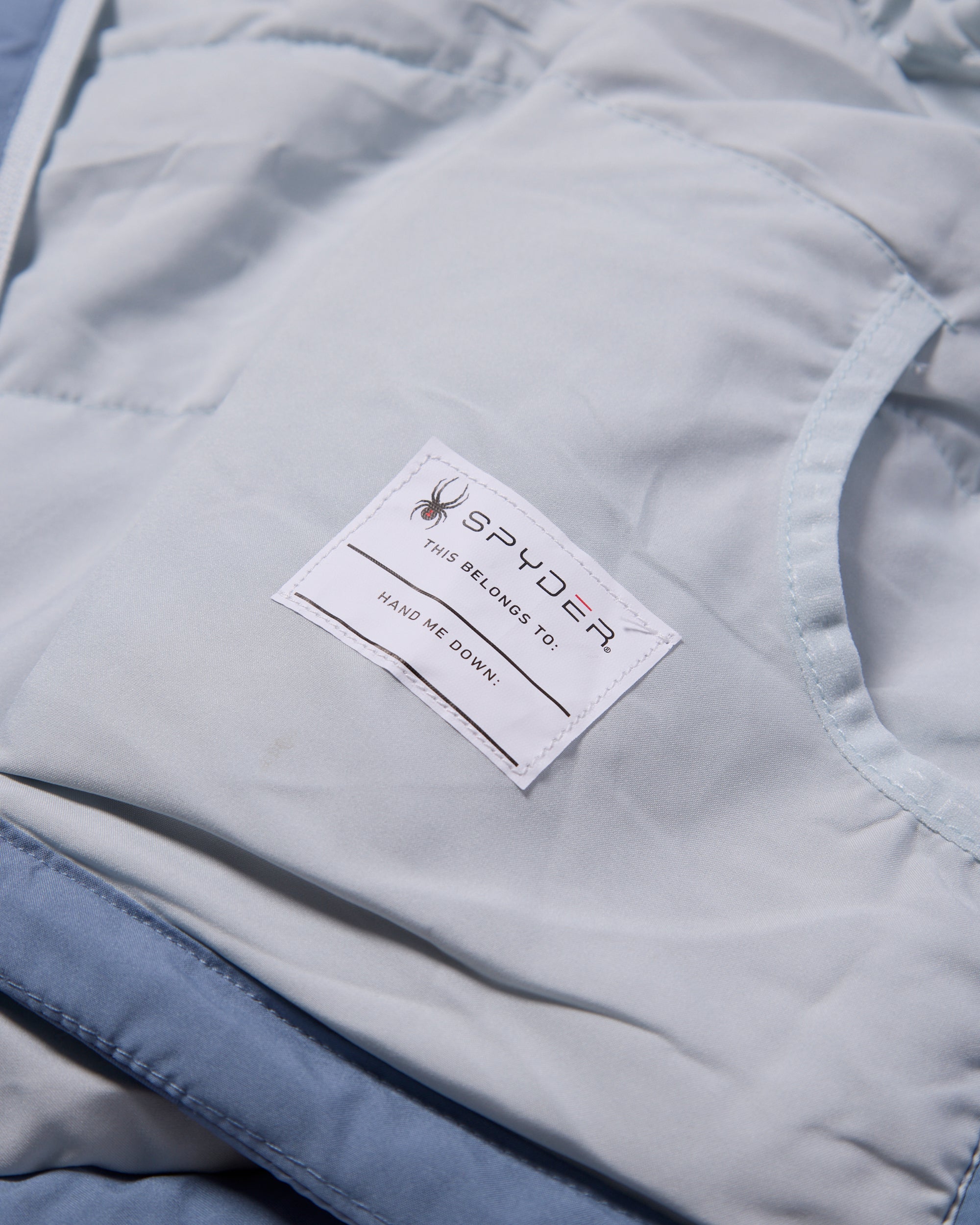 Close-up of a Spyder label on a light gray jacket